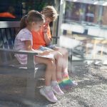 Fraser Woods Montessori School students enjoying Book Buddies reading program on outdoor bench at Newtown CT campus